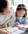 The 5-Year MFGM Advantage Follow Up Study: Little girl doing her studies with a glass of MFGM fortified milk at the table